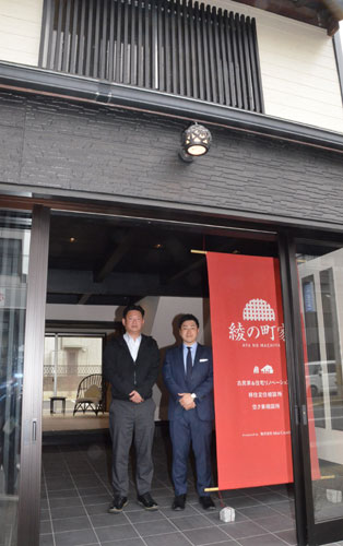 ６月開業予定の「綾の町屋」玄関に立つ中村さん（左）と羽賀さん。ロゴは建物の雰囲気やイメージを表現する＝写真はいずれも大島町で