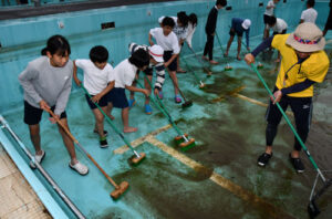 綾部小学校（上野町、小嶋康弘校長）で５月31日、プール掃除が行われた。この日は、あいにく小雨が降る天候だったが、水泳学習を心待ちにしている６年生（66人）が全校を代表して取り組んだ。